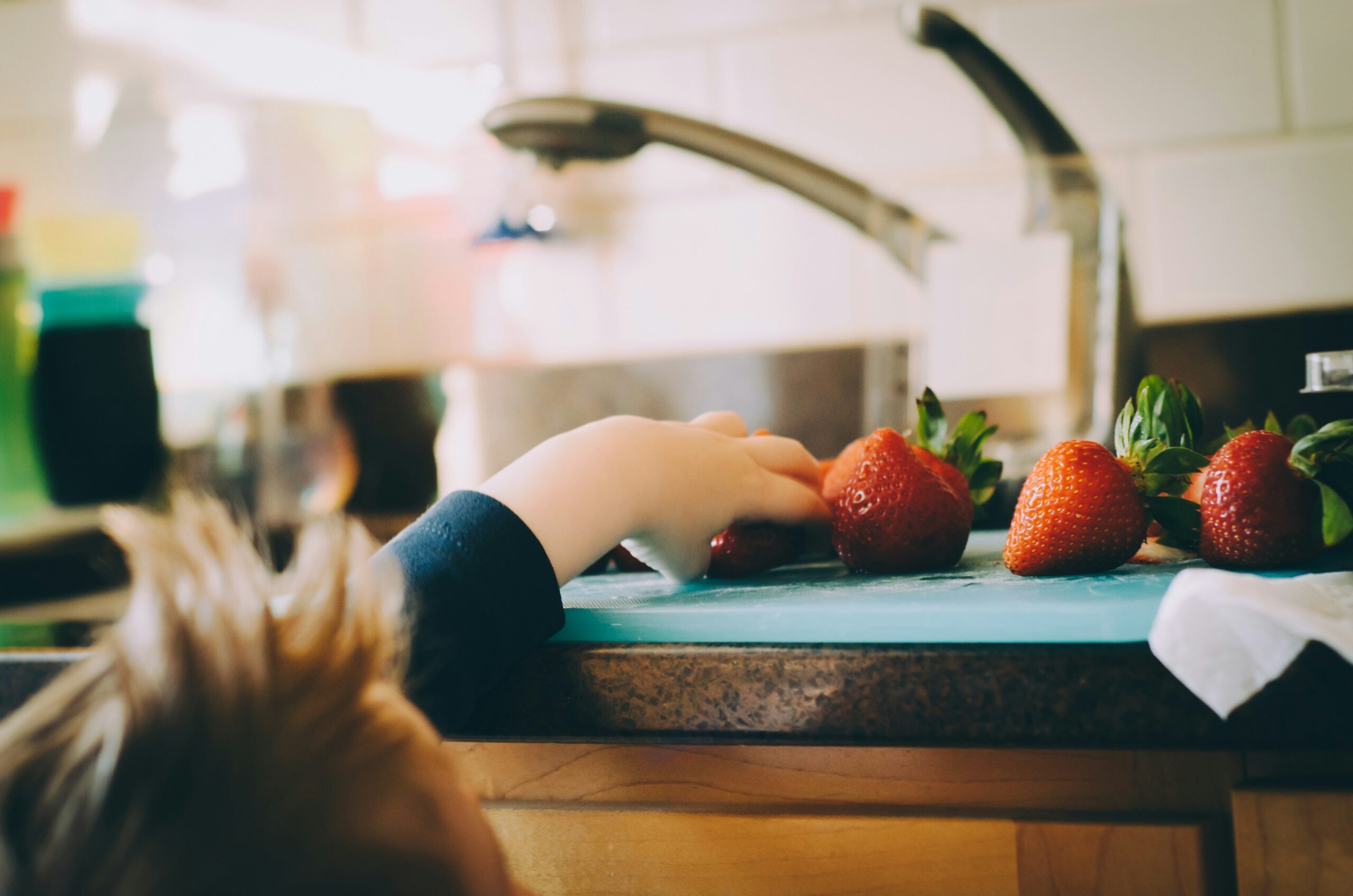 child reaching for strawberry, lying